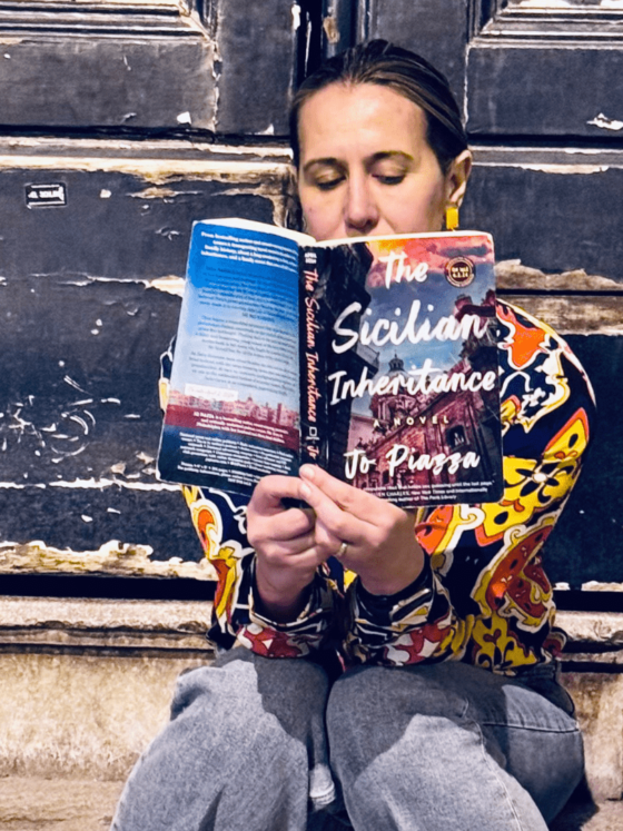 Author Jo Piazza on steps reading a book